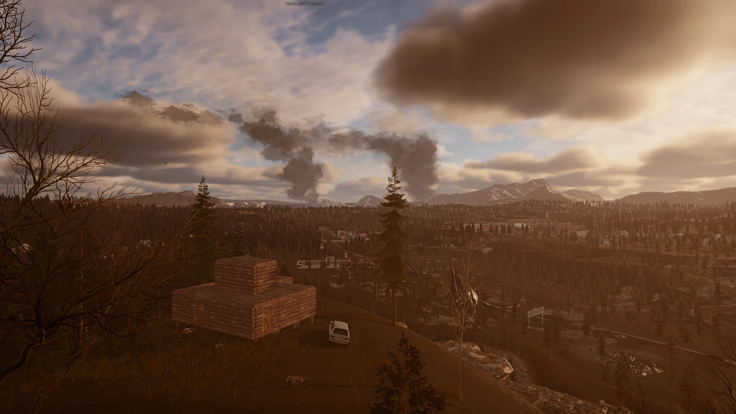 A log shelter sits on a hilltop overlooking a forested valley as smoke rises toward the mountains.