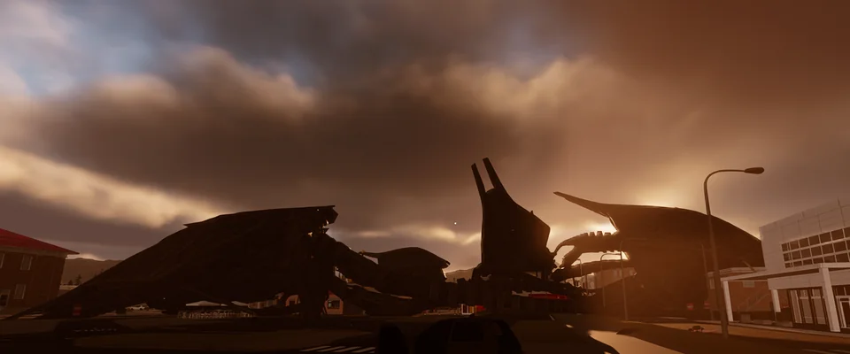 Fallen alien tripods lie collapsed across a town street at sunset.